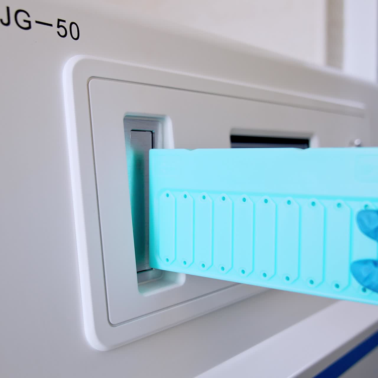 Necessary process of sterilization instruments and tool. Gloved hand of a medic placing blue plank into machine insert slot. Close up