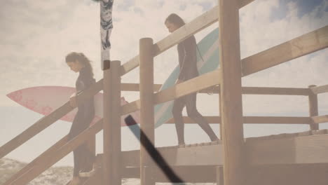 Man and woman descending boardwalk stairs, carrying surfboards, illustrating health with crucifix