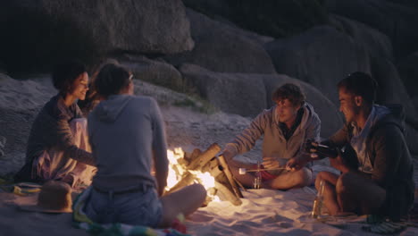 fiesta en la playa al atardecer con hoguera y malvaviscos asados con amigos