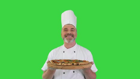 cocinero senior feliz con una pizza en las manos mirando a la cámara en una pantalla verde, llave de croma