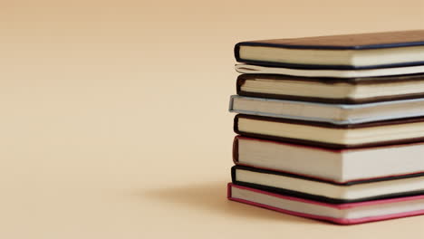 a stack of hardcover books is set against a warm beige background, with copy space