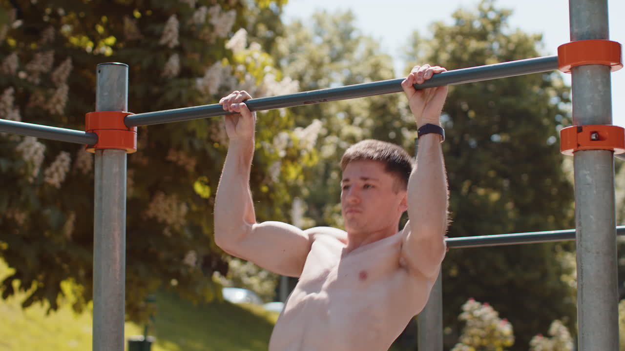 Athletic caucasian topless muscular man doing pull ups exercises on horizontal bar pumping up back