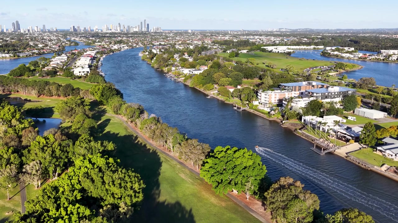 Ampia ripresa aerea con drone di lussuose case sul lungofiume, campo da golf e skyline della città sotto la luce del sole