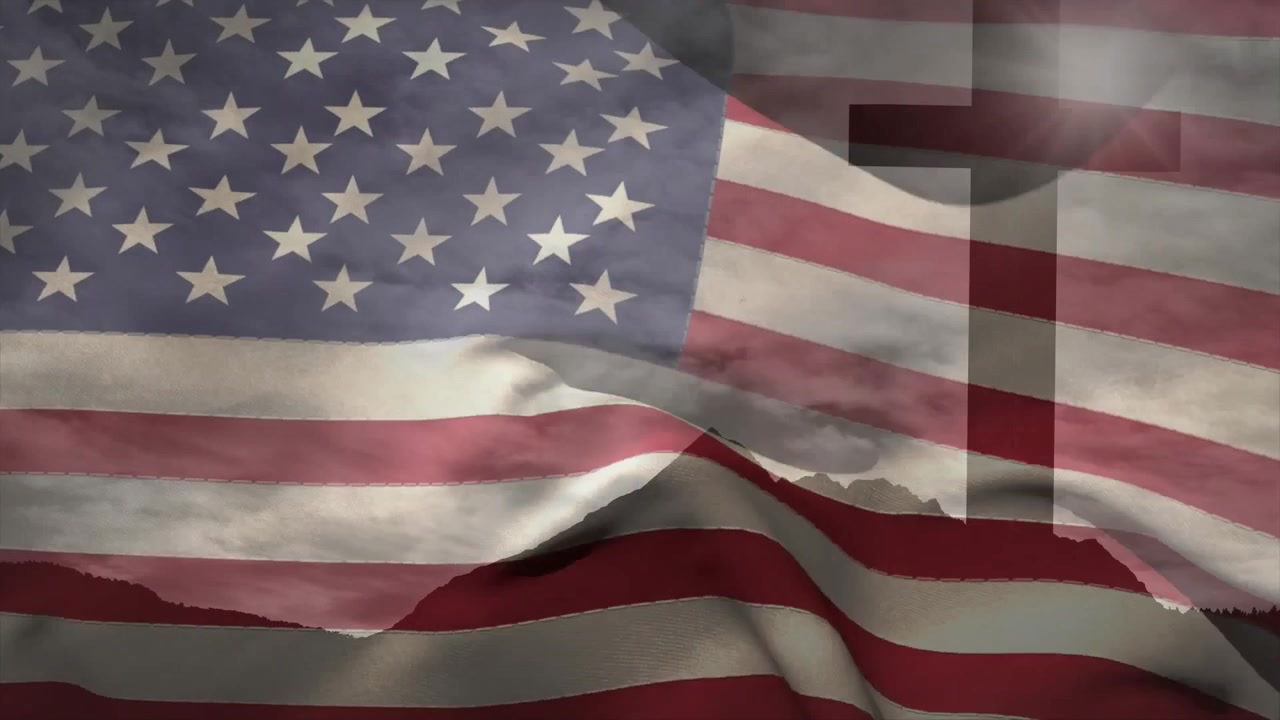 Jævn brise får amerikansk flag til at blafre over en højderyg, afslører en korssilhuet bagved.