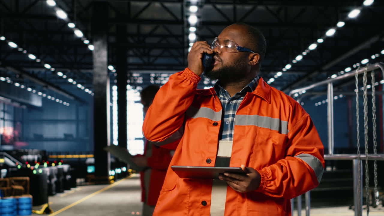 Factory worker communicates through walkie talkie near automation machinery