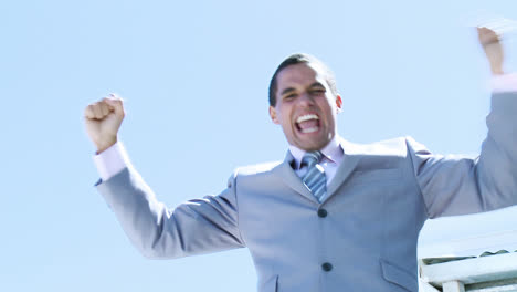 un hombre de negocios celebrando un éxito al aire libre.