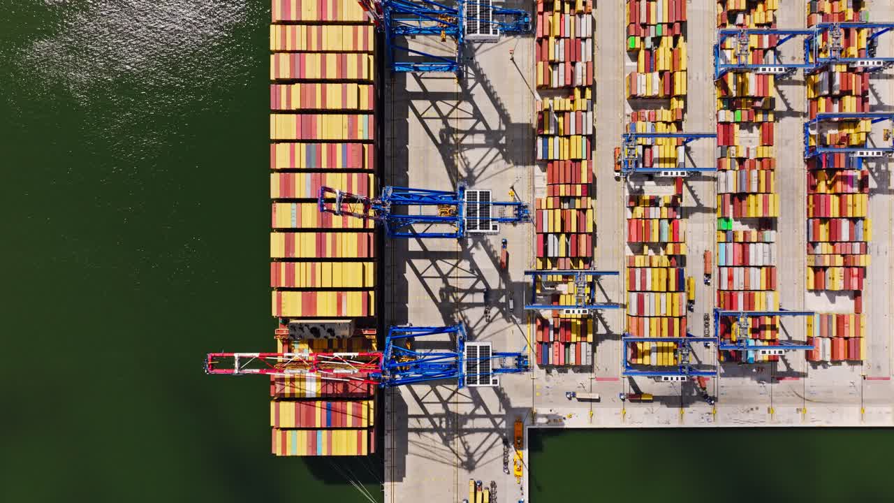 Top down aerial view of Gdansk port showing stacked containers and blue cranes