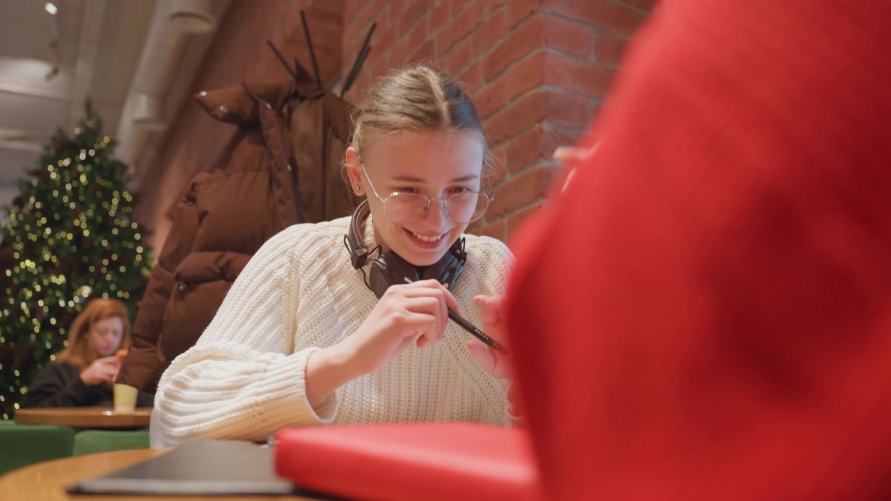 Jonge vrouw met koptelefoon praat en schrijft in café