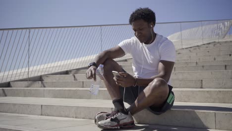 smiling african american man listening music from smartphone.