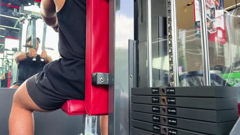 a person exercises on a chest fly machine in a well-lit gym, focusing on strength training and fitness