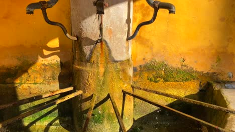 rustic old three tap fountain water running down in menton france, tilting up