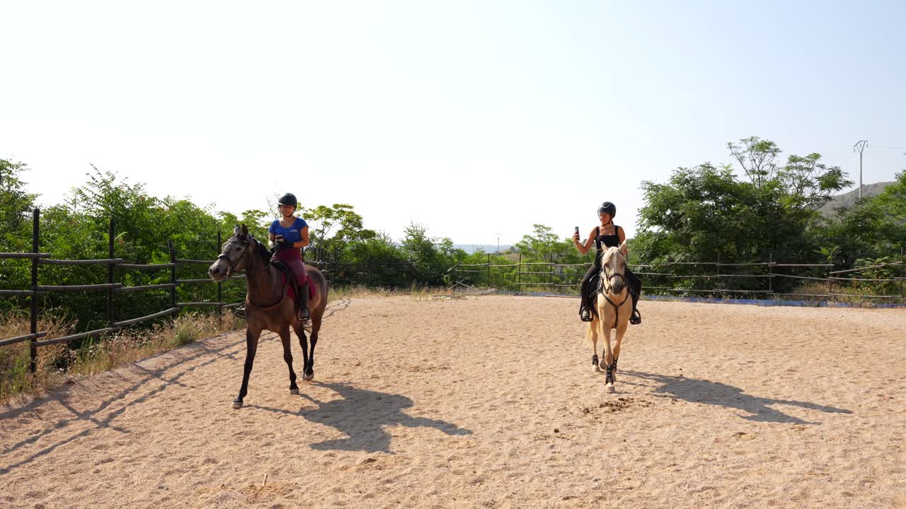 Two women take photos with phones as they ride happily along the practice course