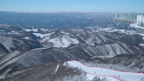 monapark rooftop view on skiers skiing down the hill of balwangsan mountain ski slope in yong pyong ski resort pyeongchang-gun and daegwallyeong mountain chain - aerial high angle skyline