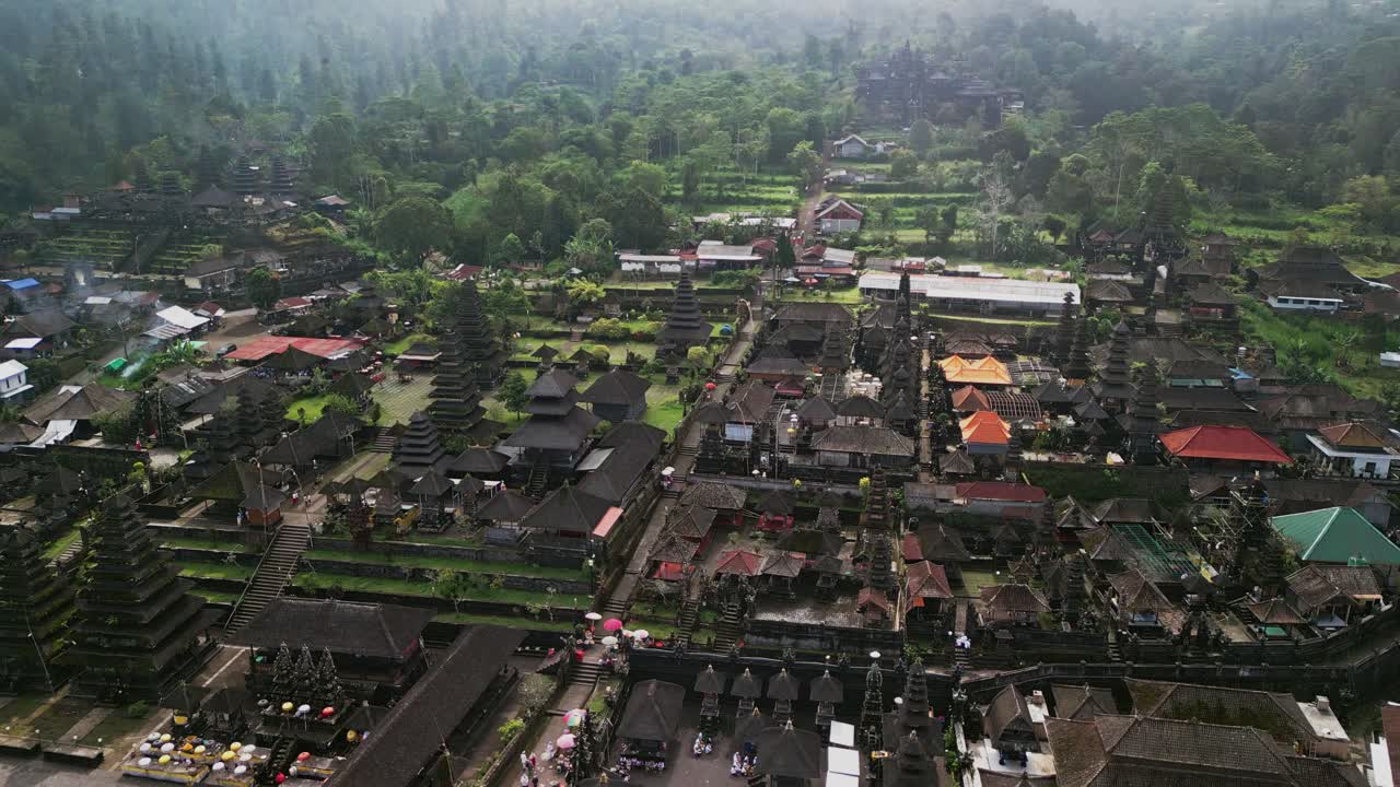 Scenic drone video capturing Besakih Temple, a historic spiritual complex on Mount Agung’s slopes, showcasing ancient stone structures, ceremonial staircases, and lush verdant surroundings in Bali