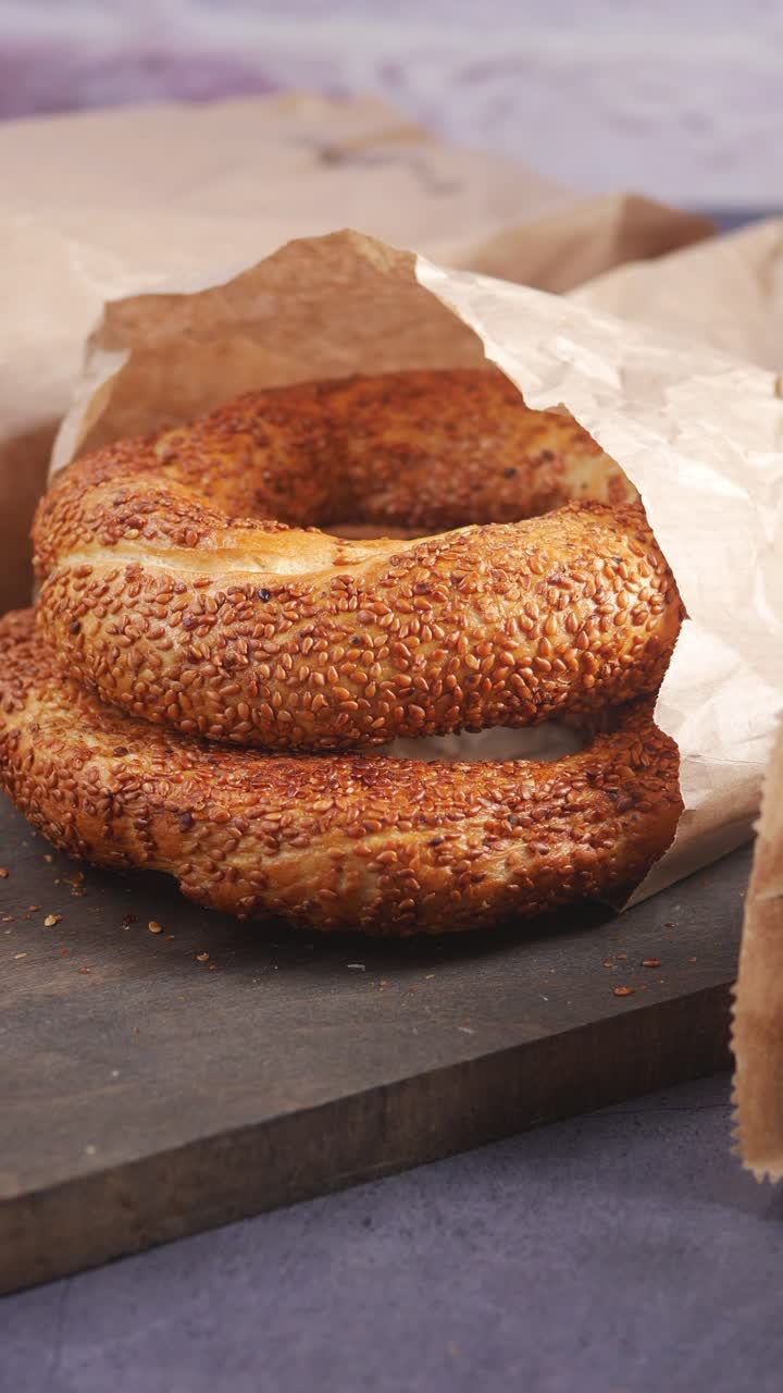 Bagel freschi al sesamo in sacchetto di carta su tagliere di legno