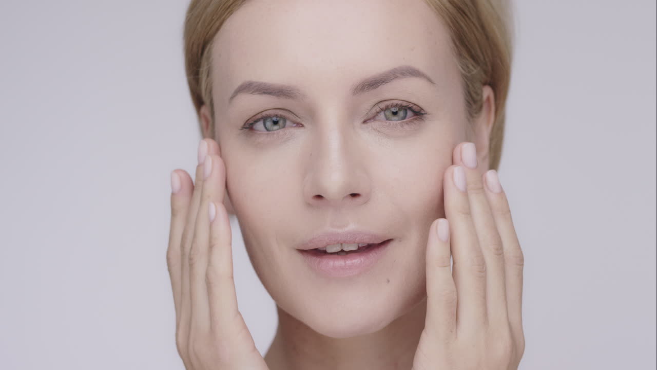 Beautiful healthy woman touching smooth skin on face in slow motion for beauty skincare concept on a grey background Red Epic Dragon