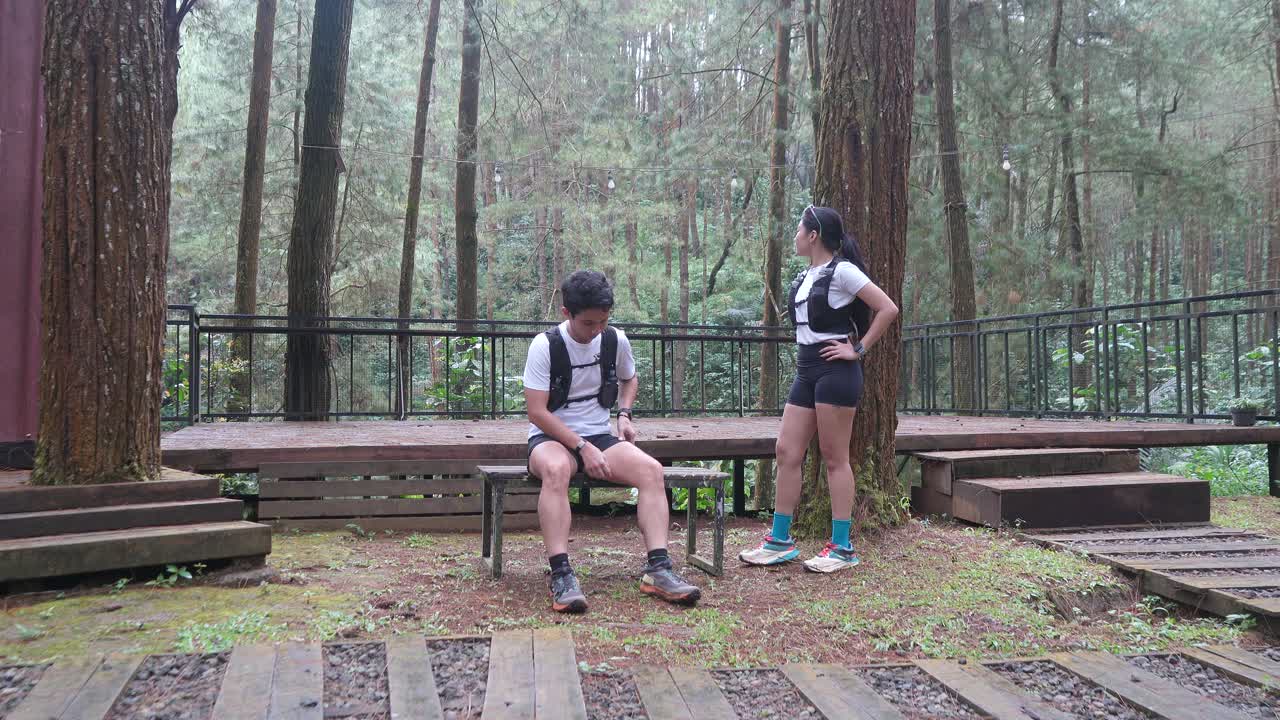 Asian couple taking photo with smartphone during outdoor trail run in Indonesian forest