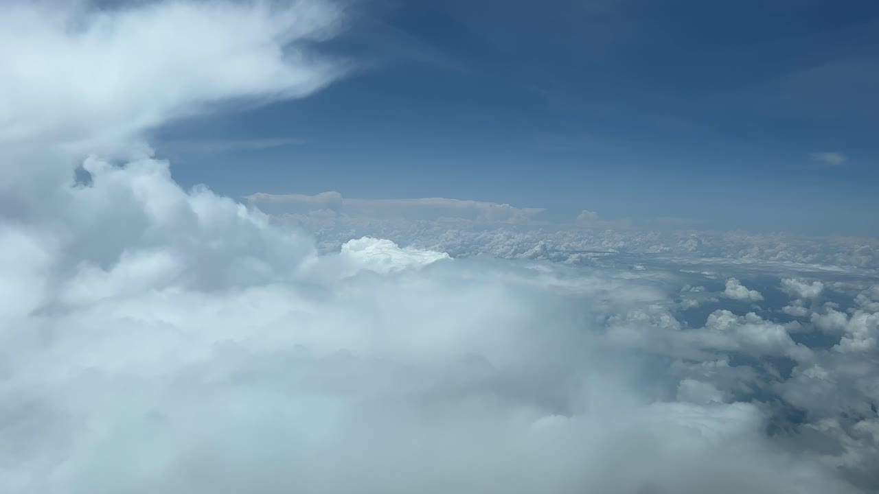 A pilot&rsquo;s point of view shot from a jet cabin flying just over fluffy clouds at 8000m high