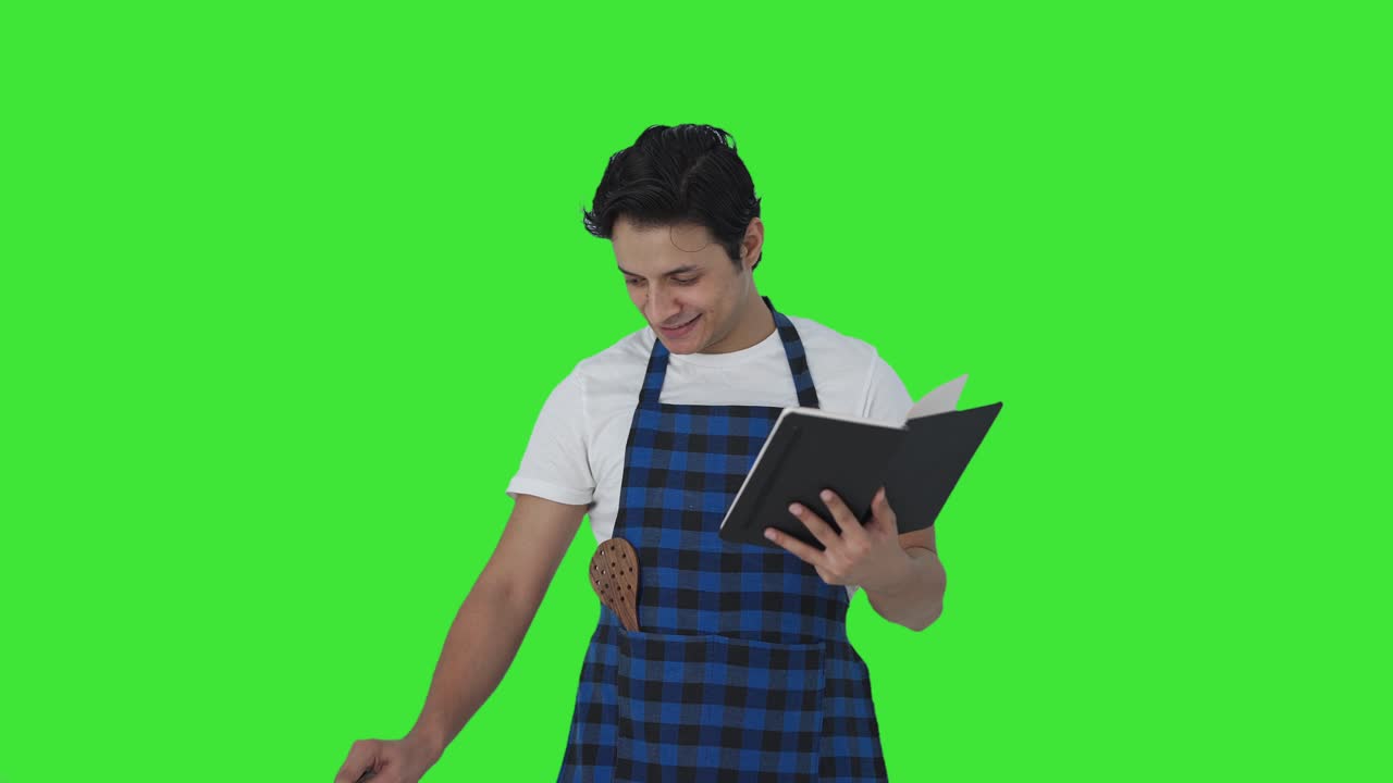 cocinero indio feliz haciendo comida del libro de recetas pantalla verde