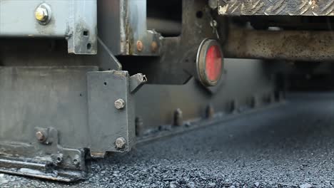 Close-up-view-of-the-road-construction-process-of-spreading,-spreading-or-placing-asphalt-mixture-materials-using-an-asphalt-paver-finisher-spreading-machine
