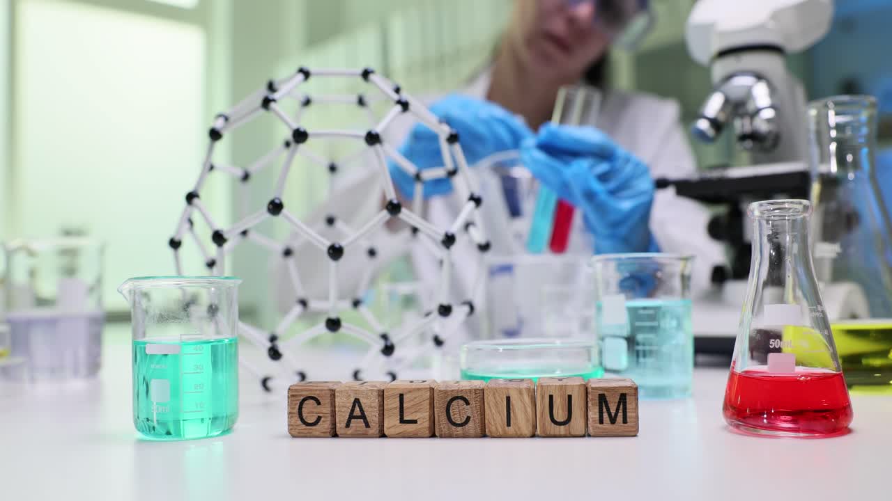 Close-up of 'CALCIUM' blocks in a chemistry lab with a blurred scientist in the background