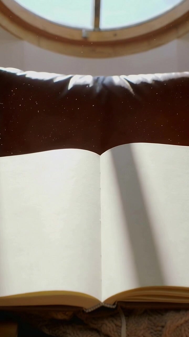 Vertical video: Drifting sunlight at window seat sweeping stripe across open journal with ribbon