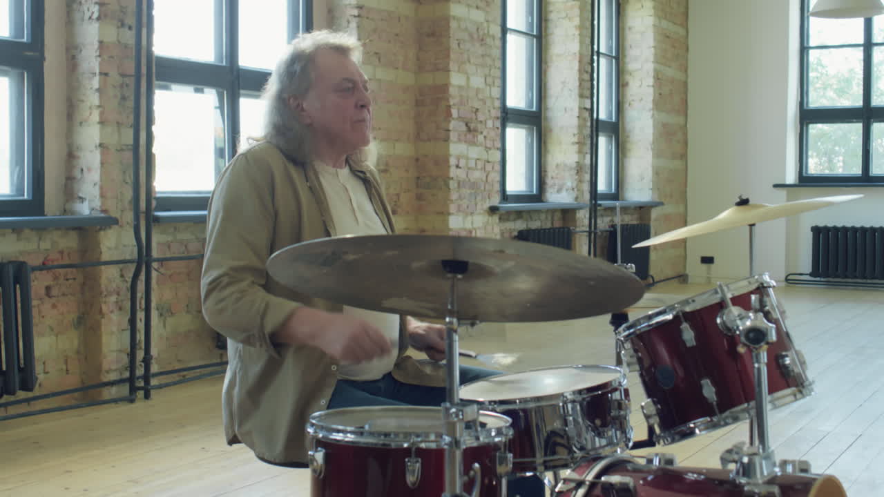 Mature Man Playing Drums in Loft Studio
