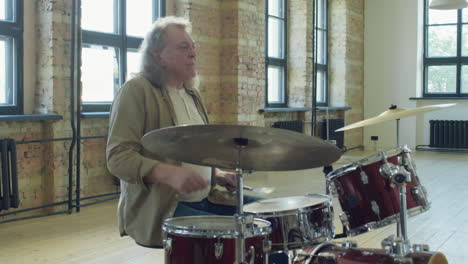 mature man playing drums in loft studio