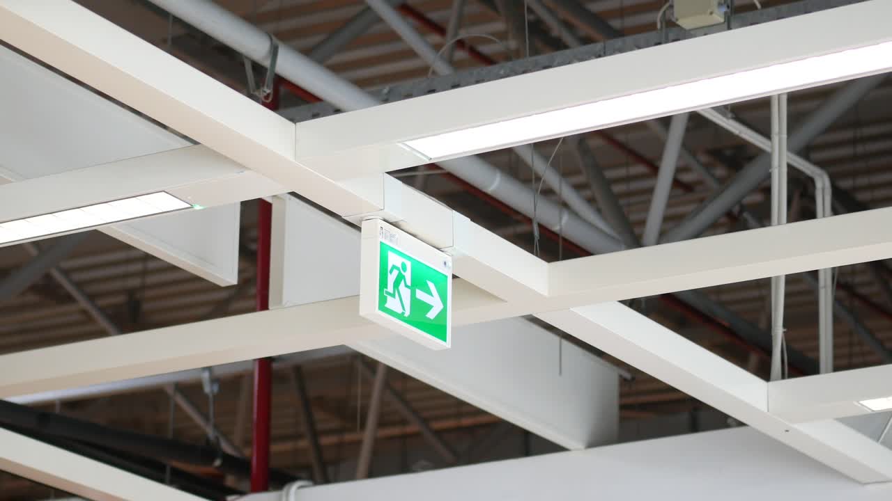 A fire exit sign hanging from the ceiling of a building