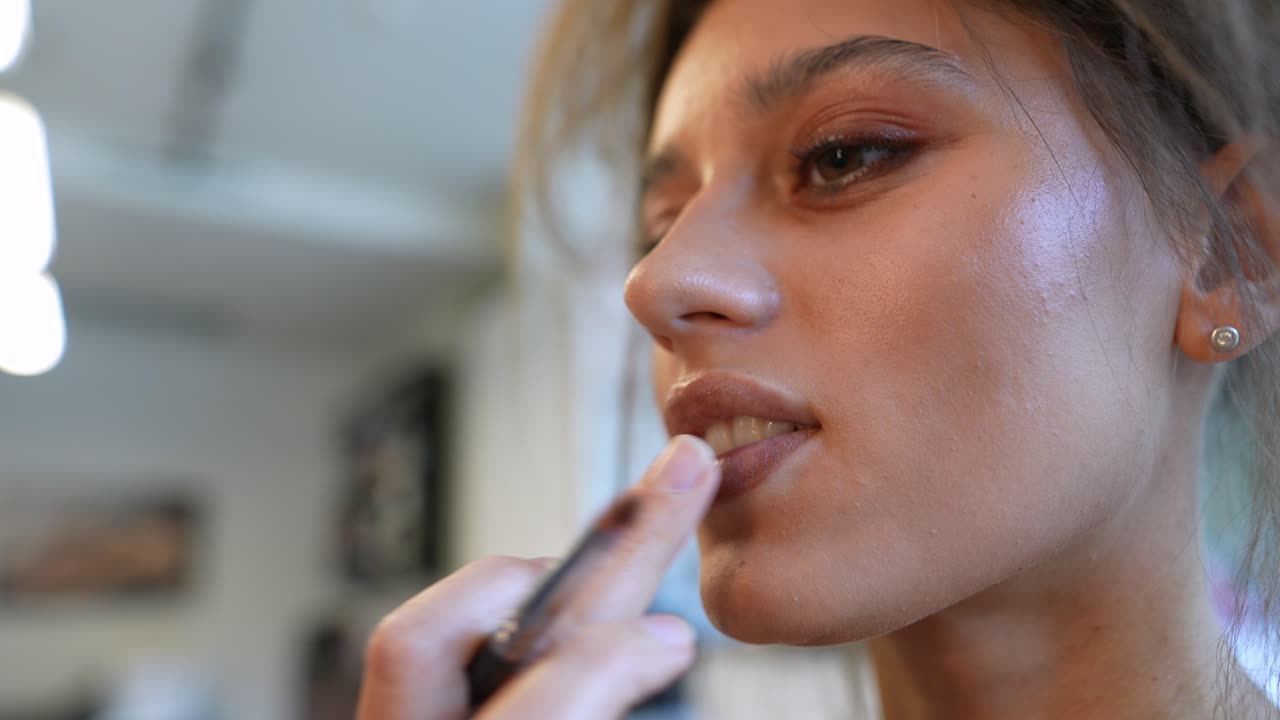 Close Up of Young Woman Applying Nude Lipstick with a Brush