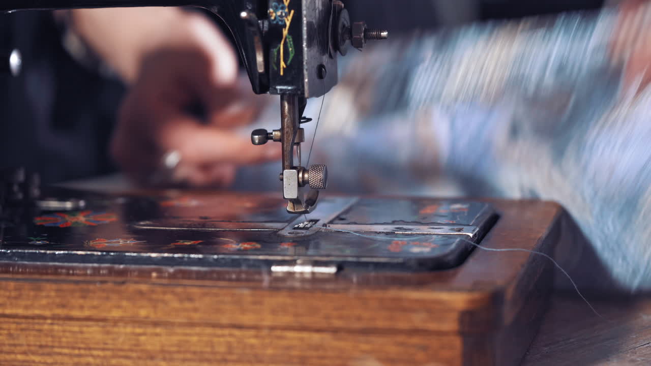 Seamstress sews clothes on machine. Close up of sewing machine and item of clothing