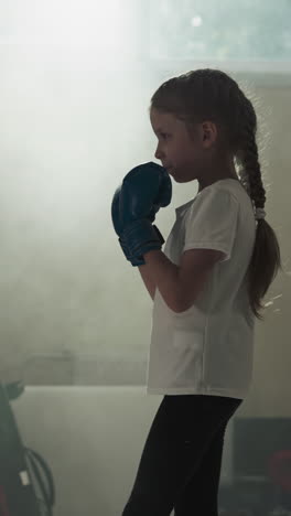 entrenador enseña técnicas de combate a niños en el gimnasio. instructor de boxeo con almohadillas para las manos habla con una niña en el club deportivo en la lección de artes marciales en cámara lenta