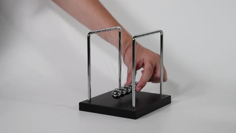 hand initiates motion of newton's cradle