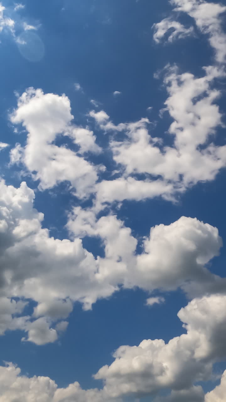 Cloudscape formation at daytime. Beautiful light cotton clouds changing shape in the blue sky. Timelapse. Vertical video