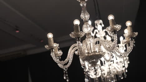 un candelabro brillante con detalles de cristal iluminado cálidamente en un entorno interior oscuro