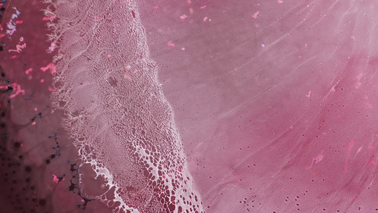 Macro shot of soft pink and magenta color ink getting blended together