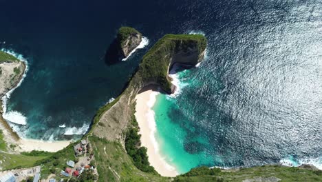 drone footage capturing a wide aerial orbit of kelingking beach in bali, indonesia, highlighting the turquoise waters, dramatic cliffs, and the surrounding landscape