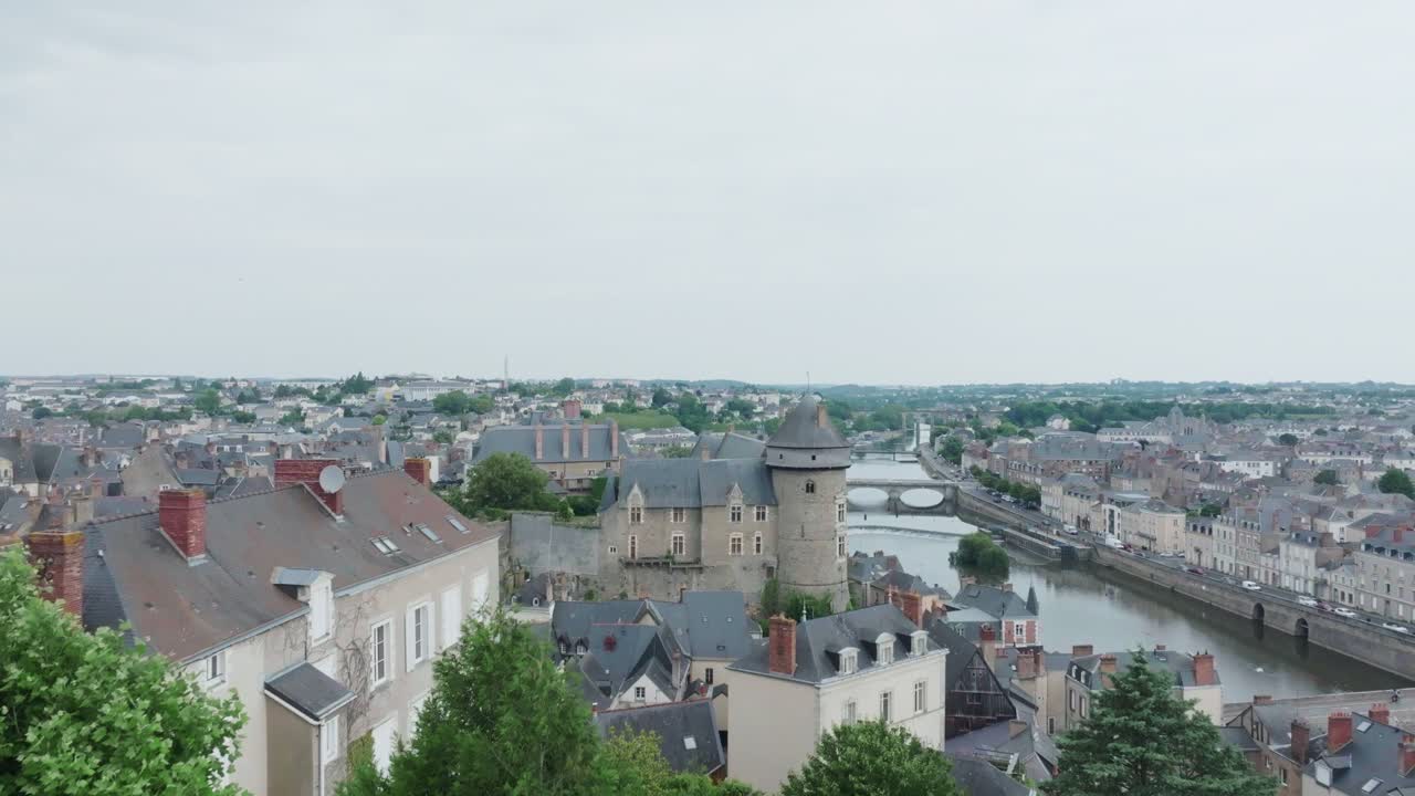 Ripresa aerea con drone che rivela il castello di Laval da dietro un albero verde, a Mayenne, Francia