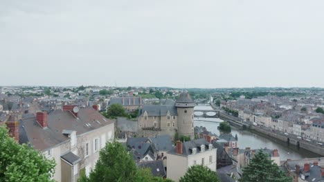 Revela-Una-Toma-Aérea-De-Un-Dron-Del-Castillo-De-Laval-Desde-Detrás-De-Un-árbol-Verde,-En-Mayenne,-Francia