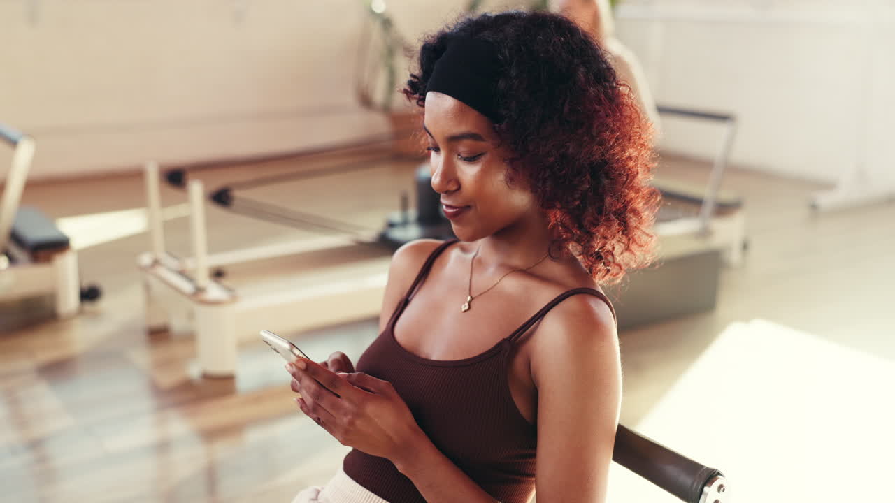 Mulher usando o celular em estúdio de pilates
