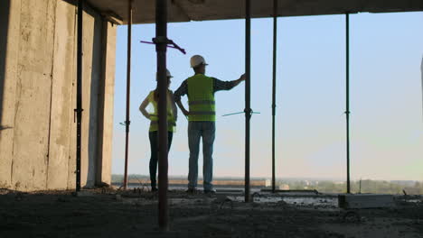 negocio de construcción: concepto de trabajo en equipo: joven ingeniero de pie detrás mirando un sitio de construcción con un casco de seguridad