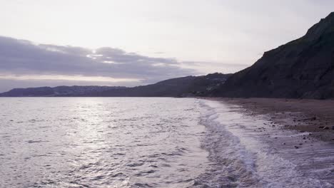 Langsame-Drohnenaufnahme-In-Zeitlupe,-Die-Sich-Von-Wellen-An-Der-Jurassic-Coast,-Dorset,-Großbritannien,-Vorwärtsbewegt