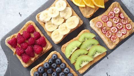 rebanadas de pan integral con mantequilla de maní y varias frutas