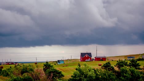 pesadas nubes grises atraviesan el cielo sobre una casa roja contra las verdes colinas cubiertas de hierba de las islas magdalen