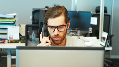 Male-executive-talking-on-telephone-at-desk