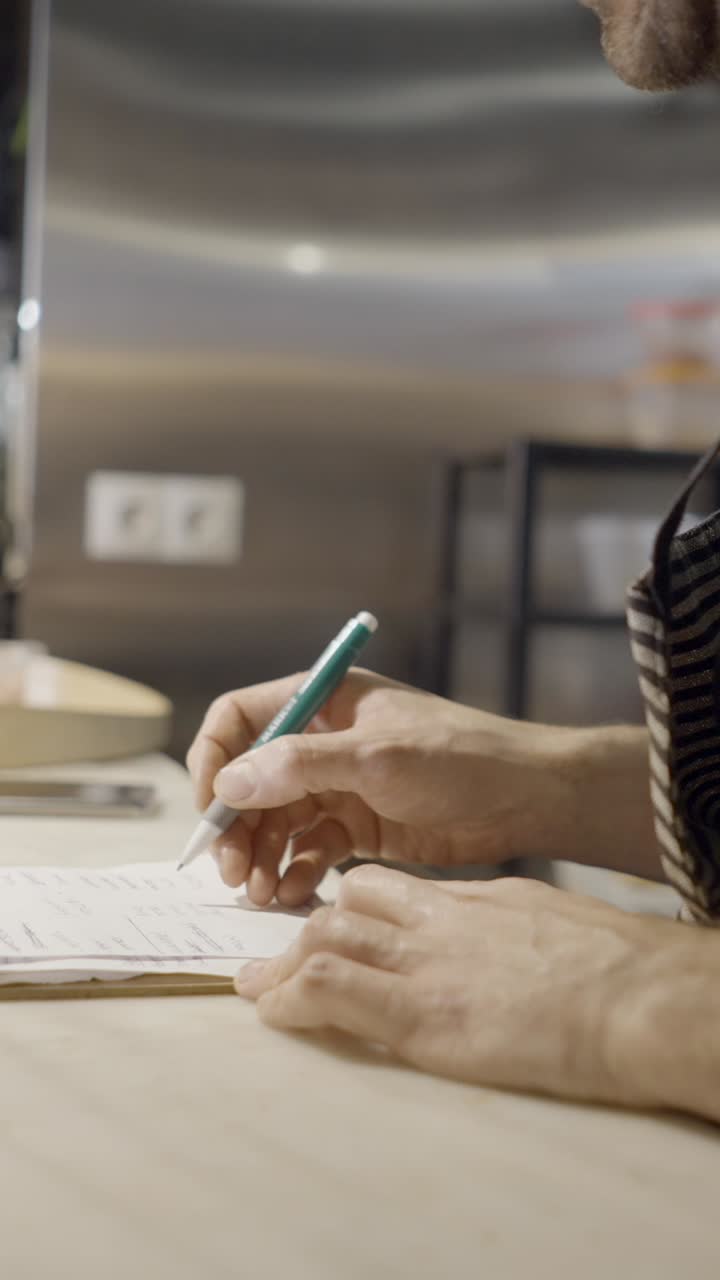 Close-up of a person writing on a notepad with a pen