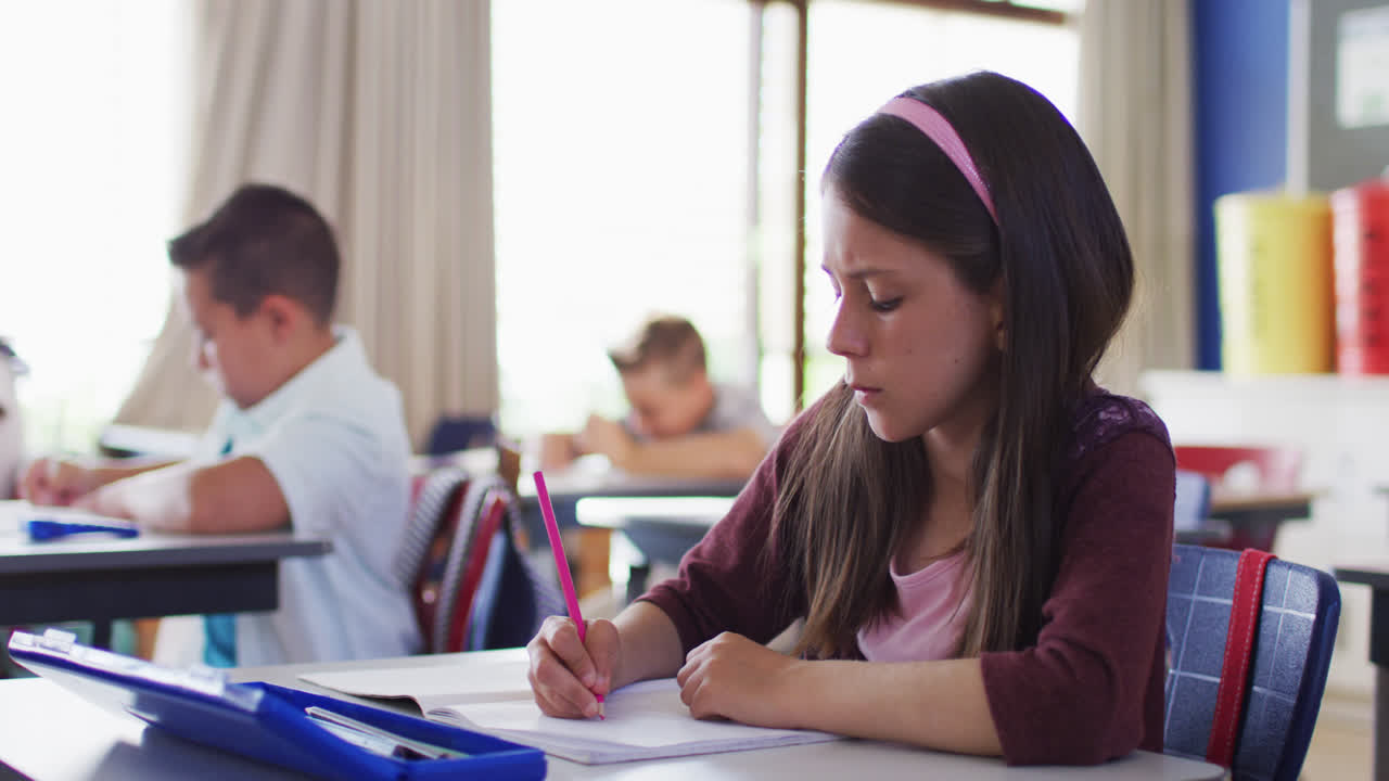 retrato de una estudiante caucásica sentada en el aula, tomando notas