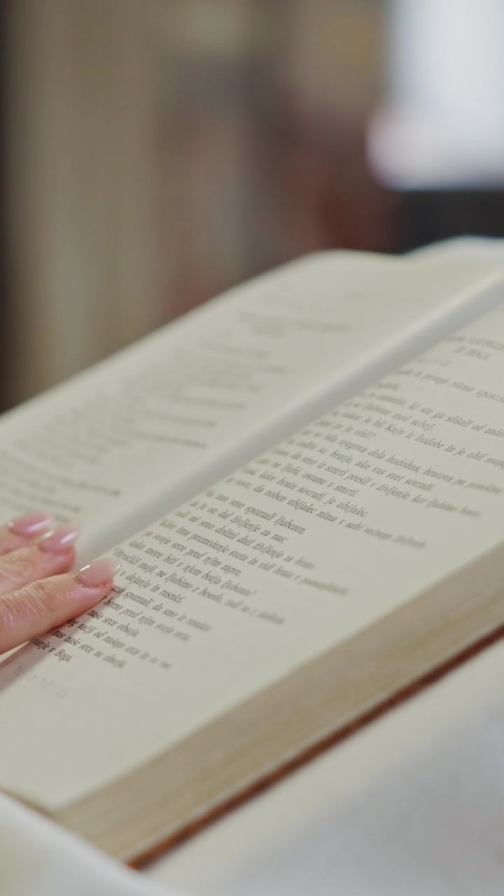 Mani femminili che sfogliano le pagine della sacra scrittura poste su un pulpito durante la messa cattolica. Donna in.