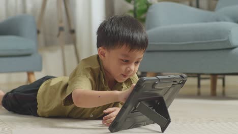 close up of asian kid lying on the floor using a tablet at home