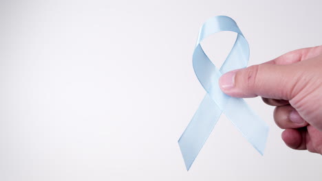 detail of male hand placing ribbon in light blue color on white background